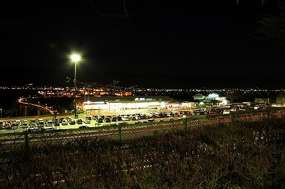 諏訪湖SA(下り線)から湖沿いの道路のライトアップと諏訪湖SA(上り線)を眺める夜景